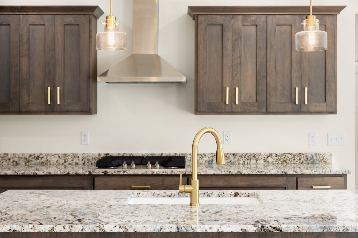 Kitchen island countertop with a gold faucet and pendant lights above