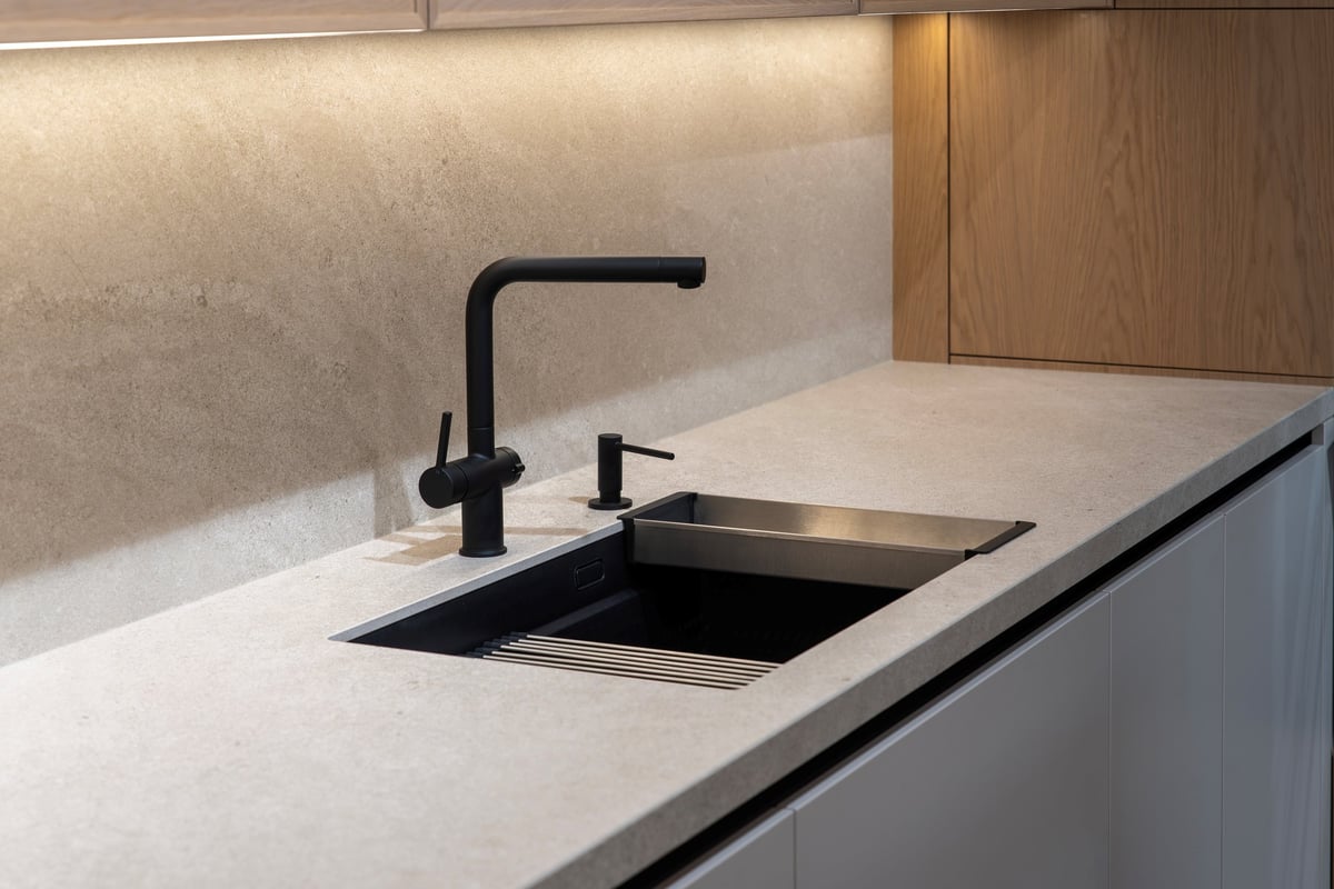 Matte black kitchen sink and faucet set into a grey stone countertop