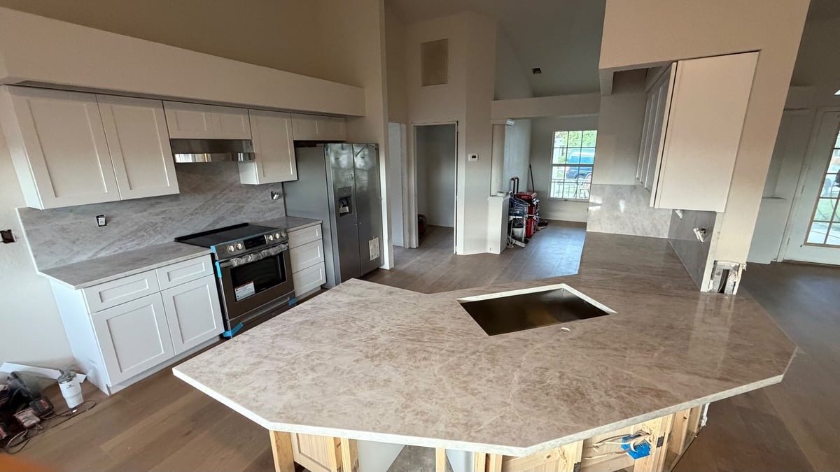 Modern kitchen with white cabinets, granite countertops, large curved island with sink, and open floor plan